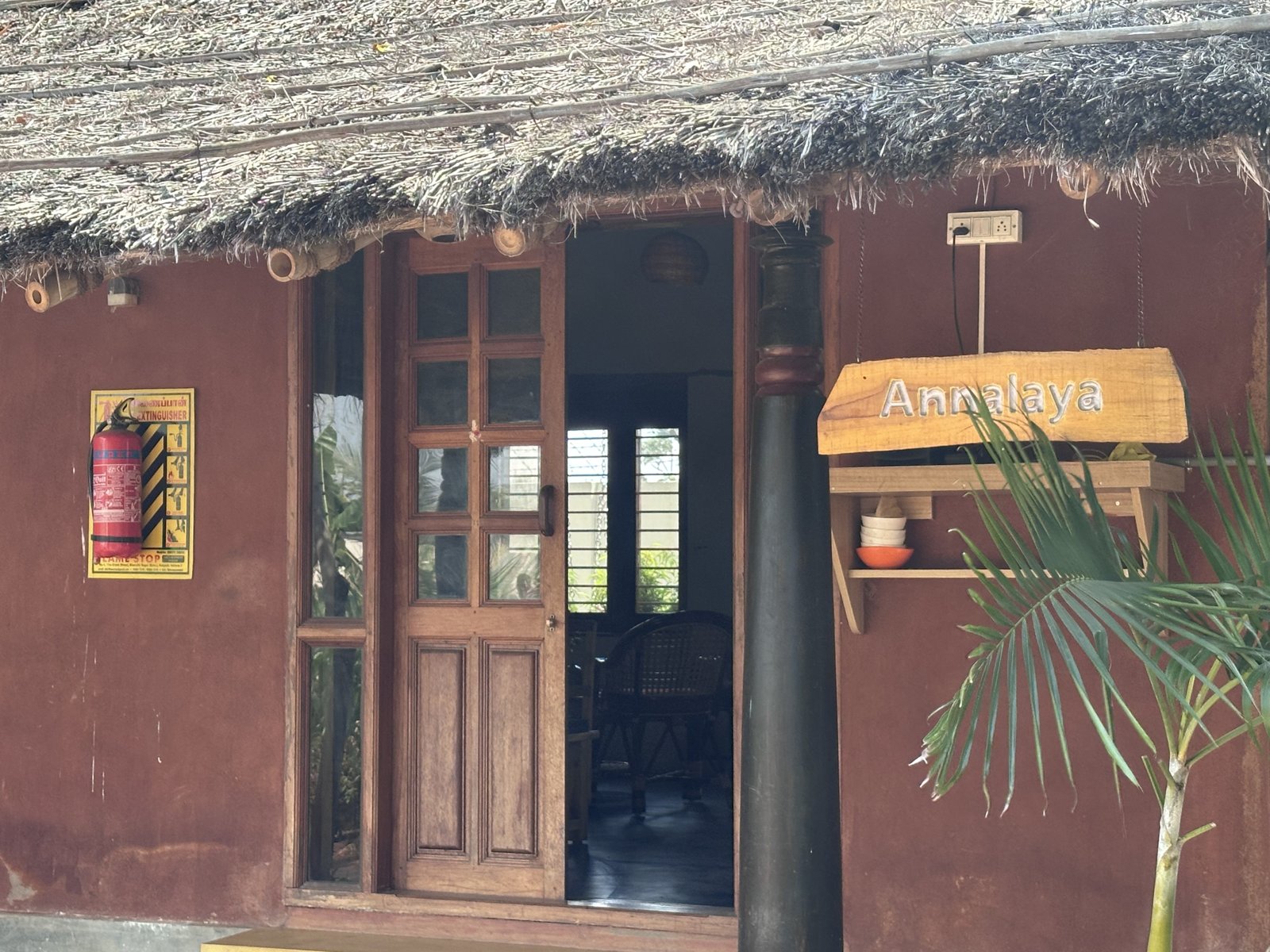 Annalaya dining hall with thatched roof and carved wooden doors