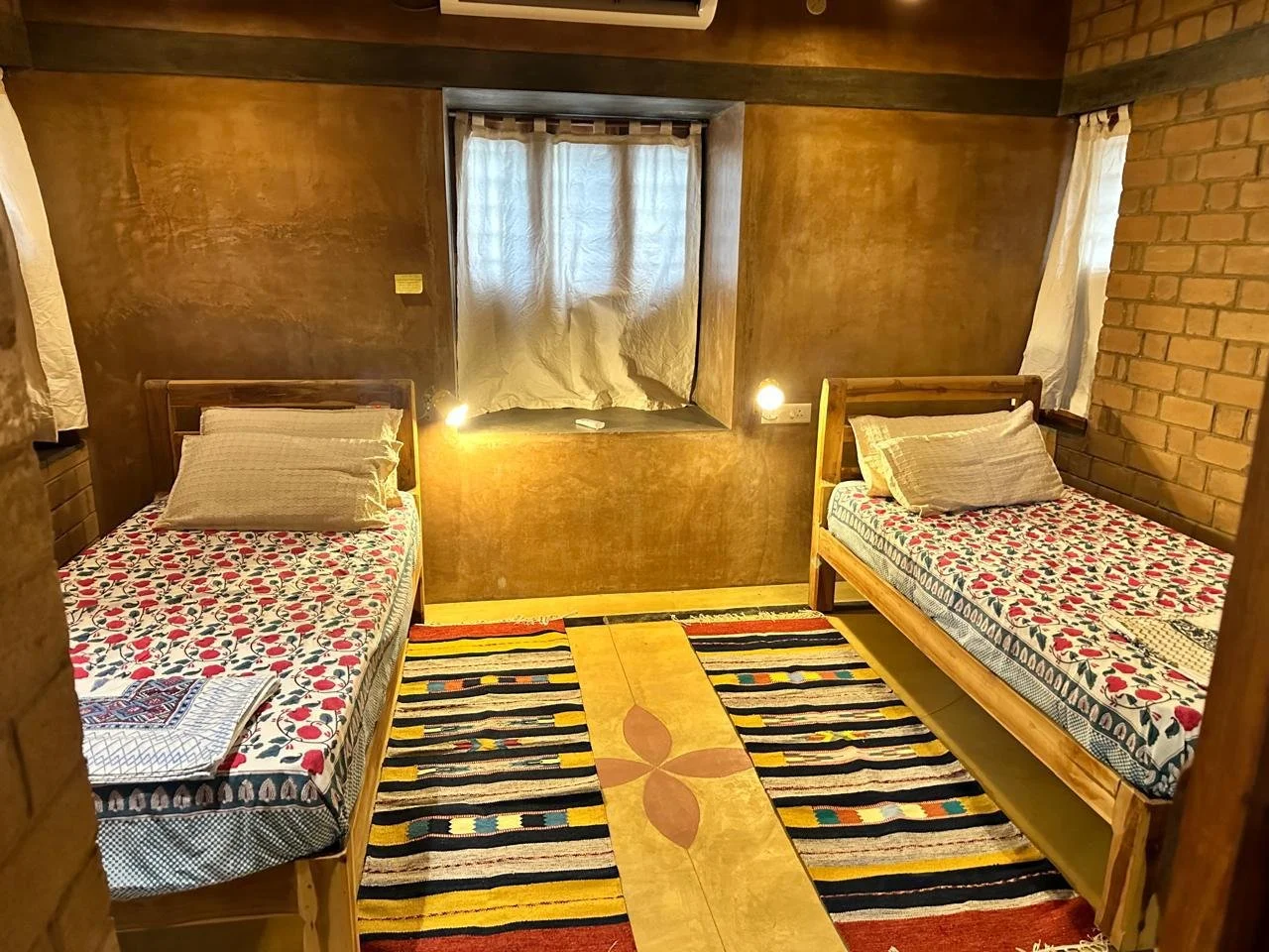 Twin bed room with teak cots, cotton linens and handwoven rugs